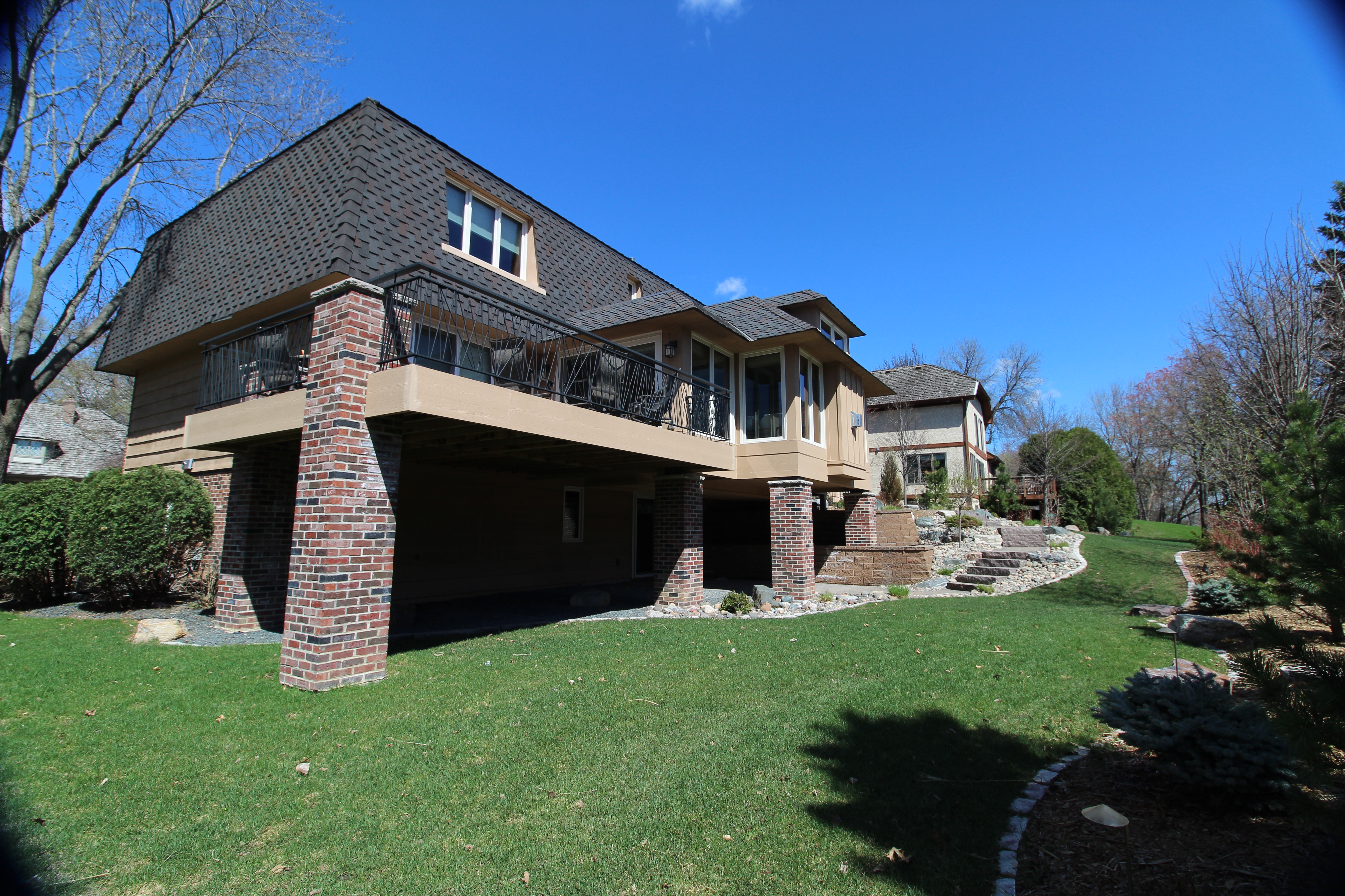 Home addition with wrap-around deck, stone pillars, and covered porch