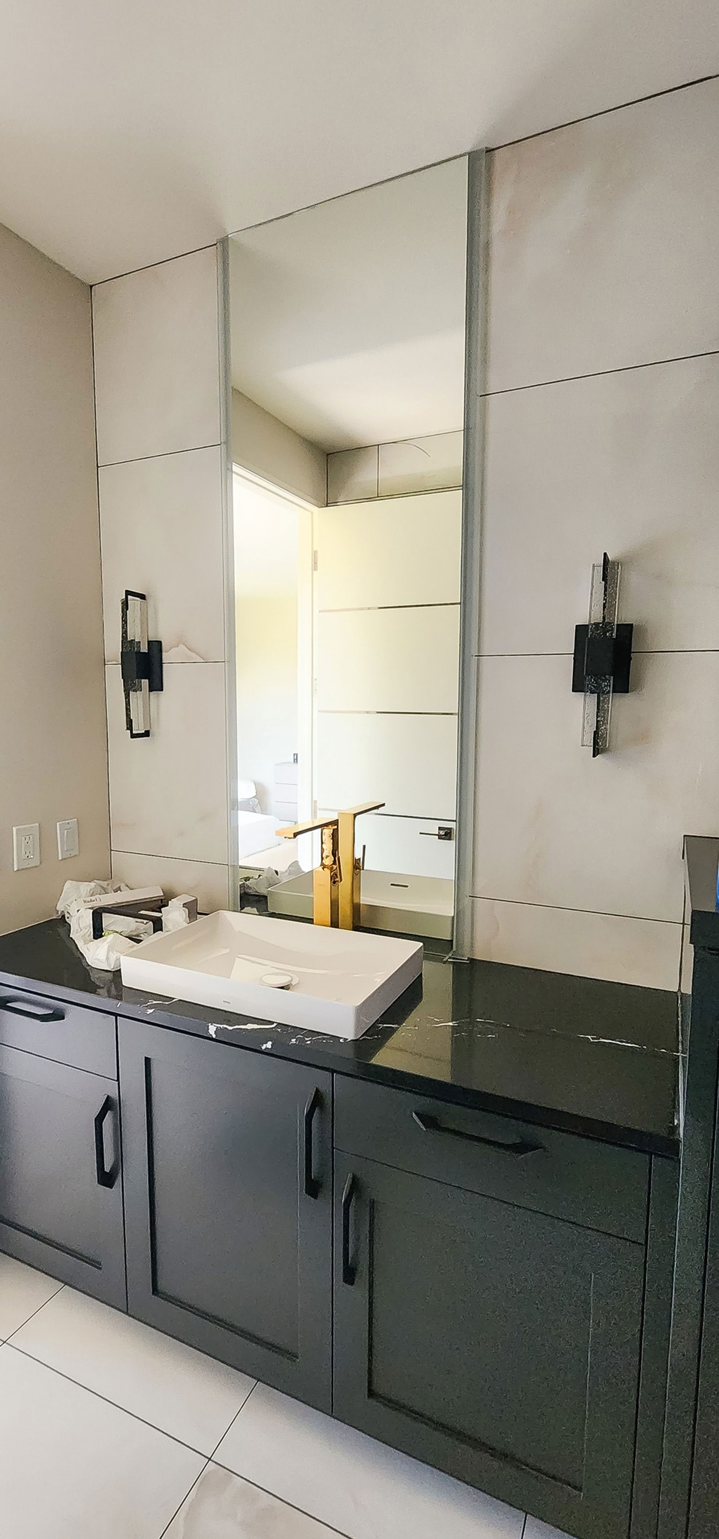 Primary bath with dark cabinetry, black stone counter, vessel sink, and pale wall tile
