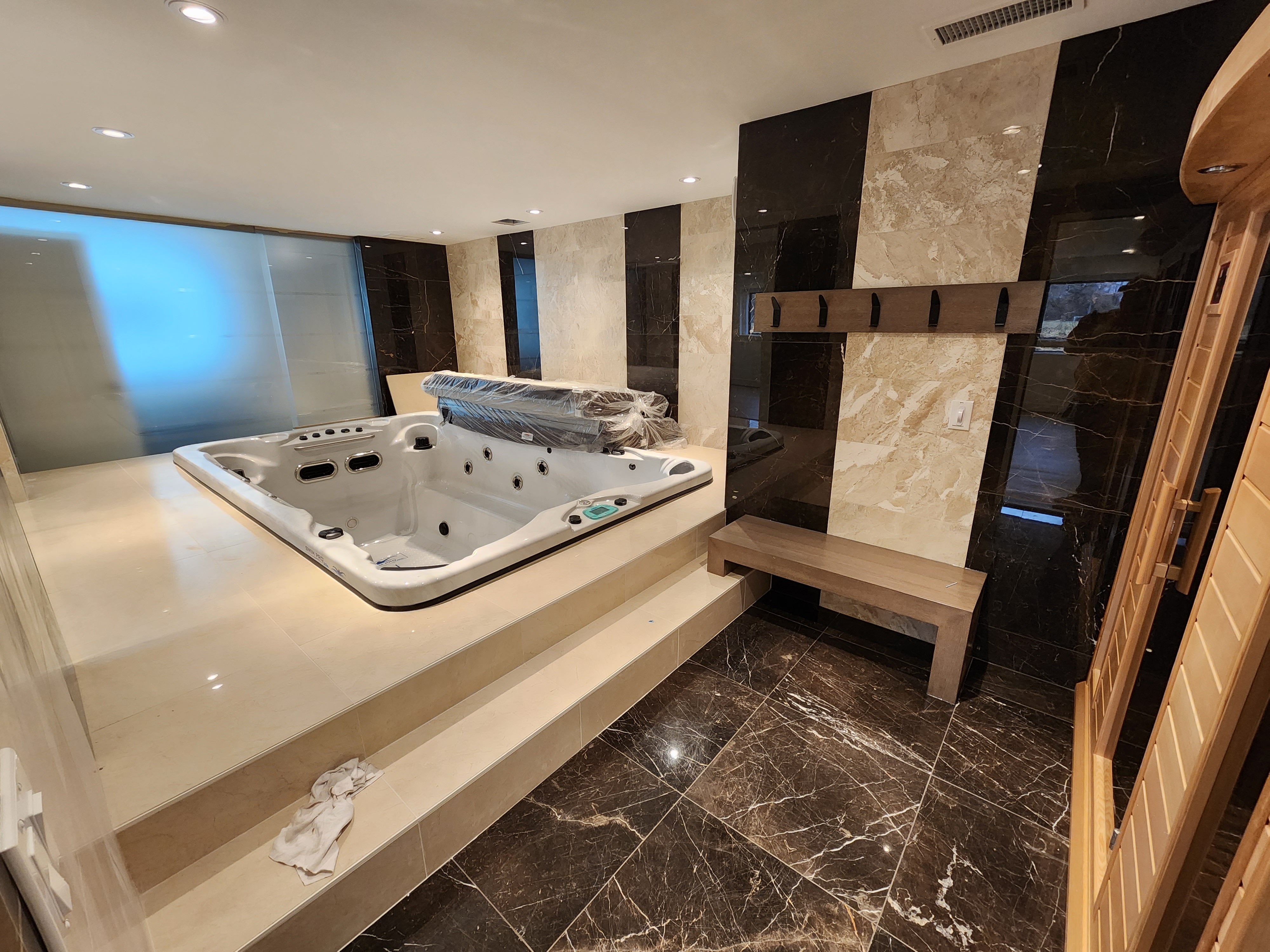 Indoor spa room with a jetted hot tub, dry sauna, and marble walls