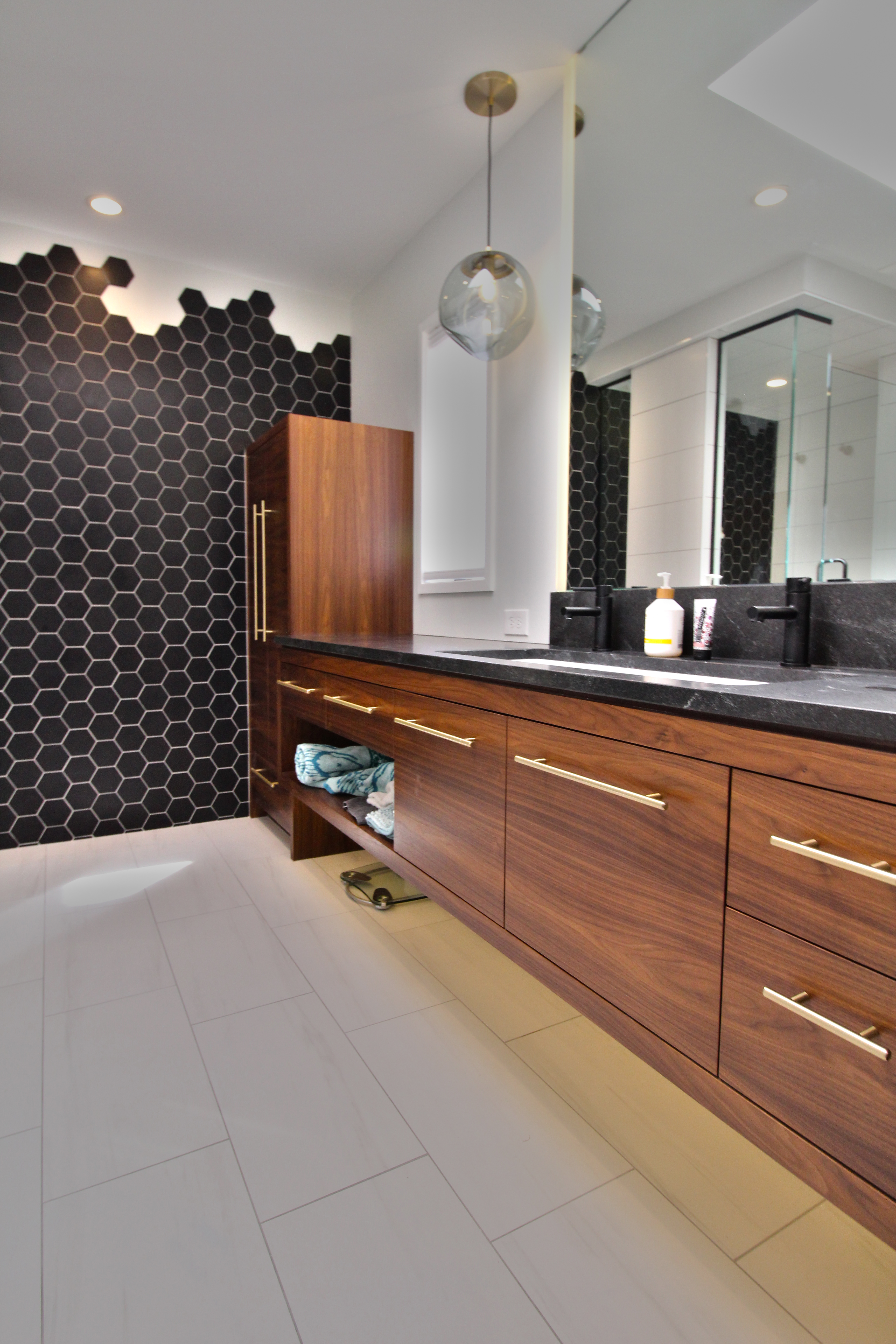 Primary bath with a floating walnut vanity, black soapstone counter, and a black hex-tile accent wall