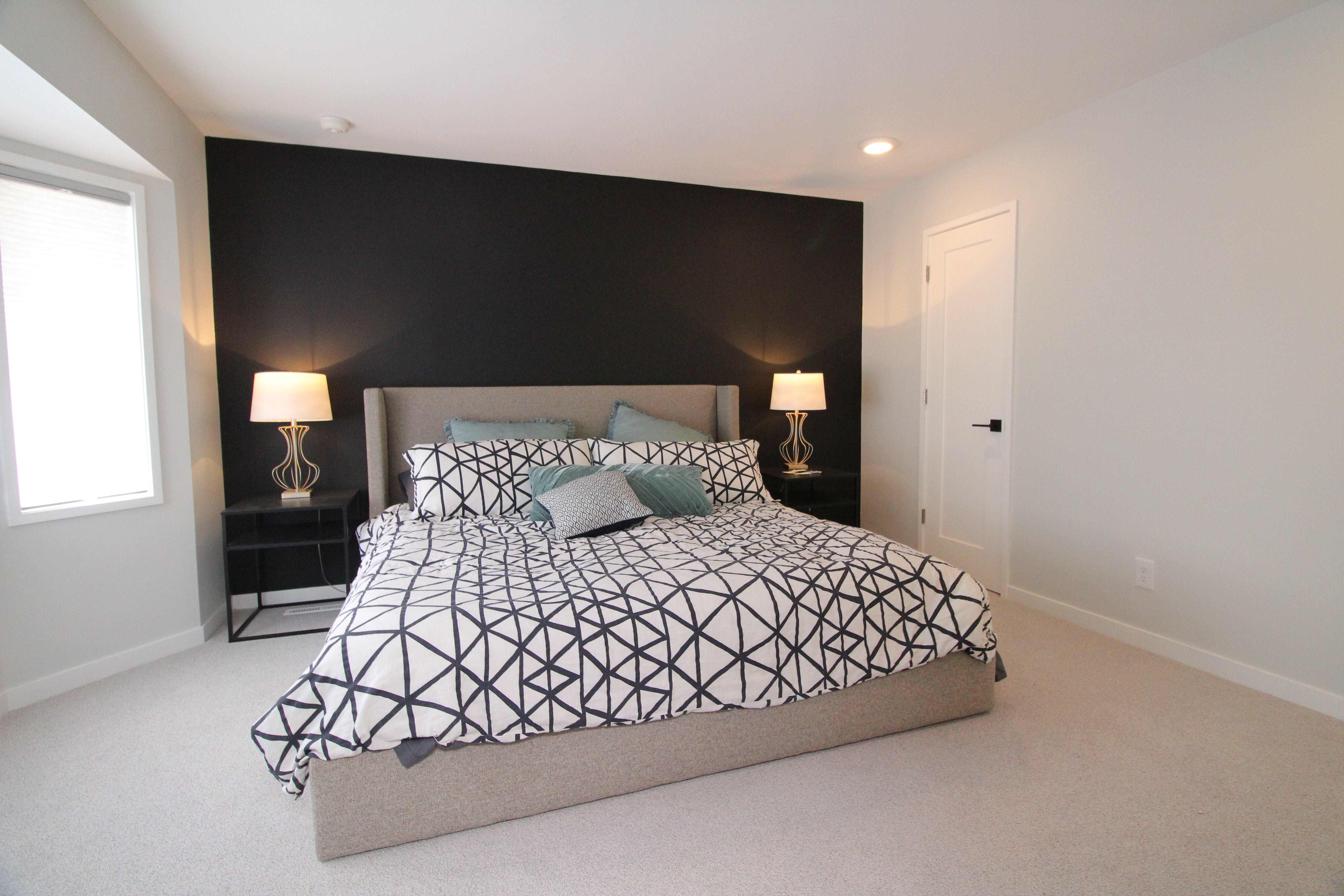 Primary bedroom with a black accent wall, upholstered bed, and matching table lamps