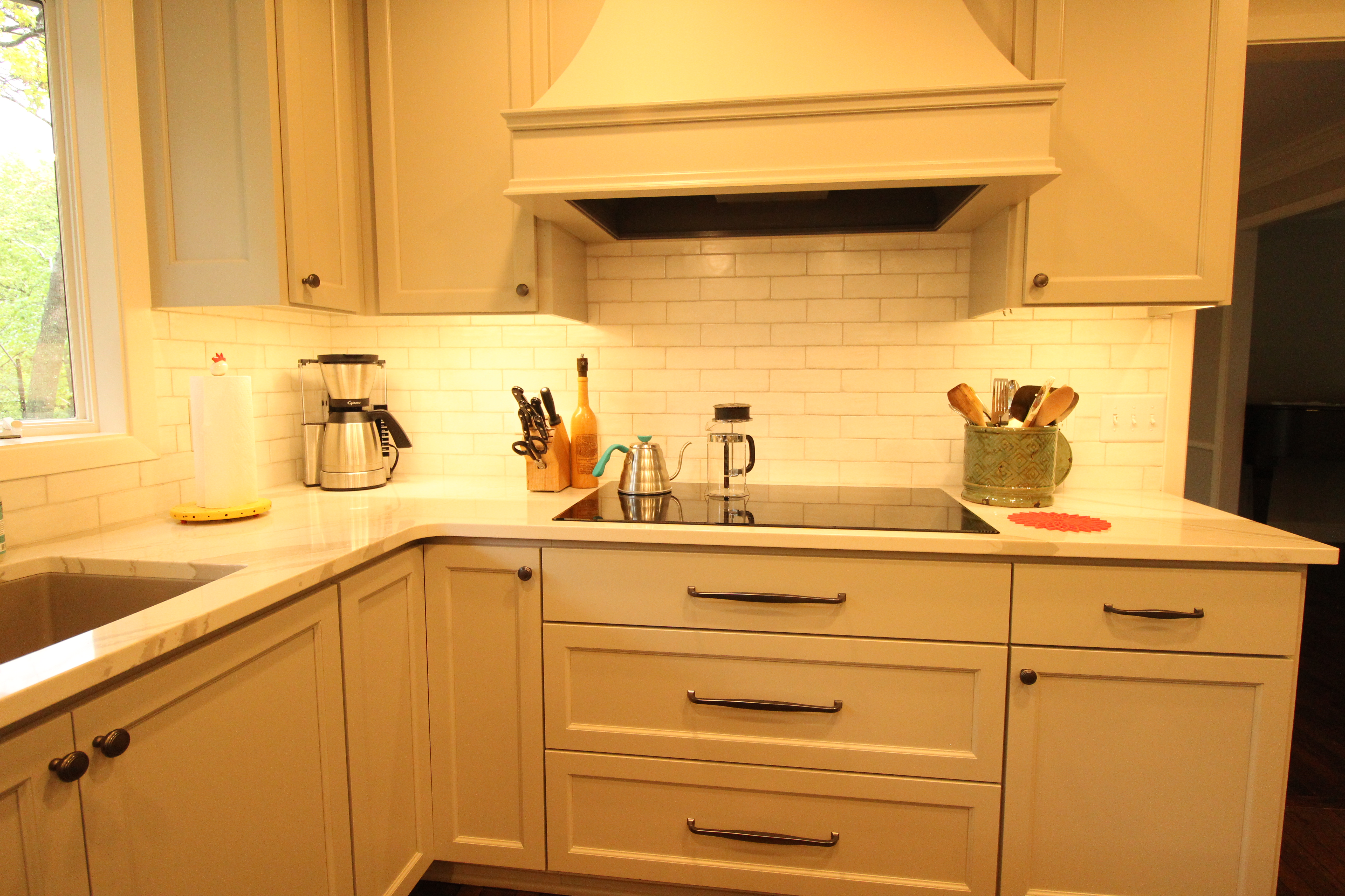 Close-up of cabinetry, subway tile, and the custom range hood