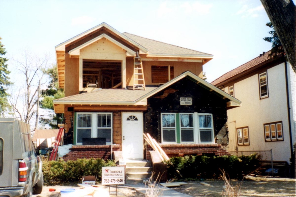 Expanded upper story with exposed sheathing and weather barrier during construction.
