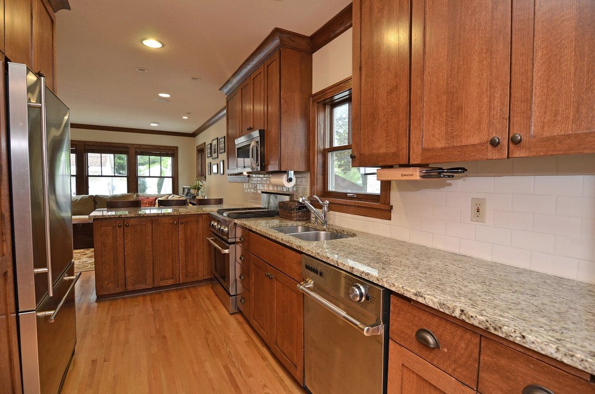 Kitchen with wood cabinetry, stone countertops and wood window trim.