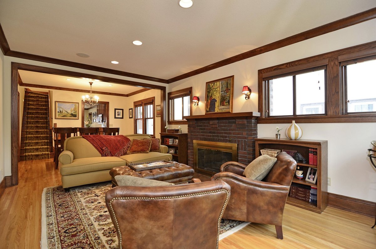 Living room with a brick fireplace, wood trim and windows on two sides.