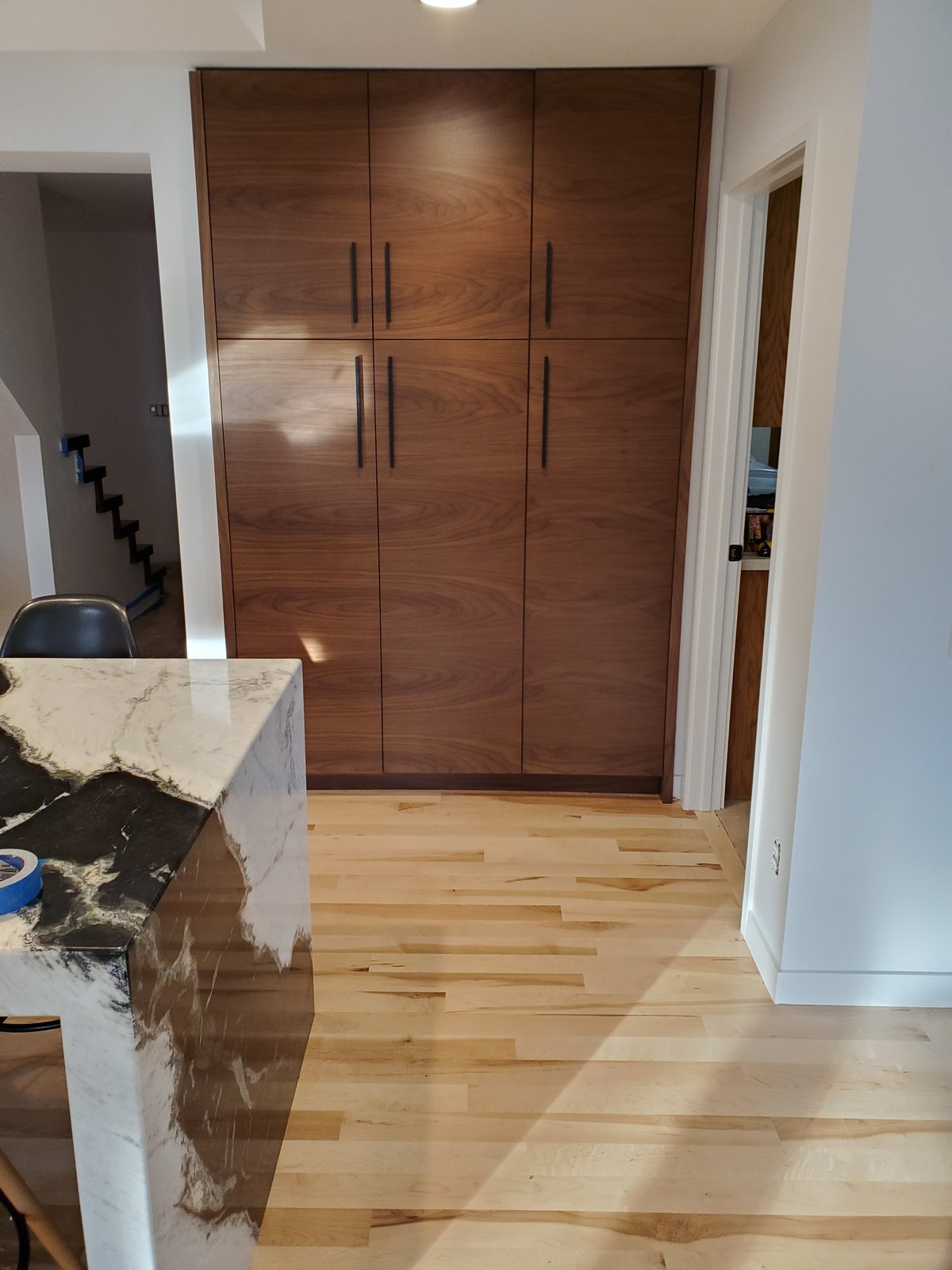 Tall walnut cabinet doors beside the edge of a stone waterfall island.
