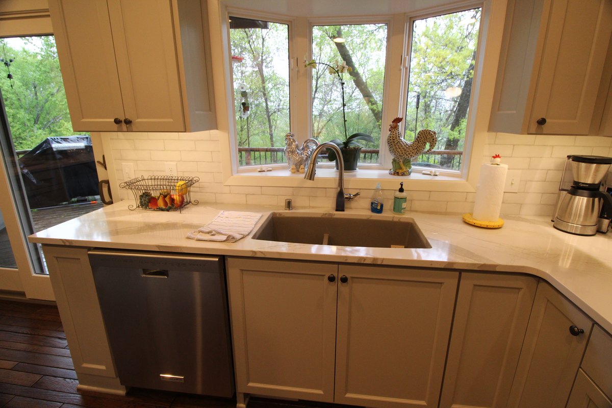 Kitchen sink and quartz counter beneath a wide window.