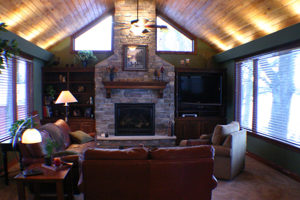Family room with a vaulted wood ceiling, a stone fireplace and built-in cabinets.