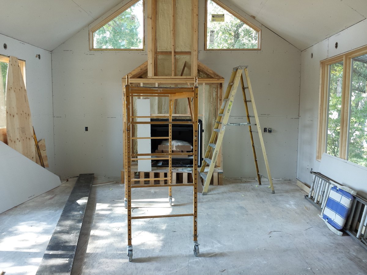 Family room during construction with unfinished fireplace framing beneath gable windows.