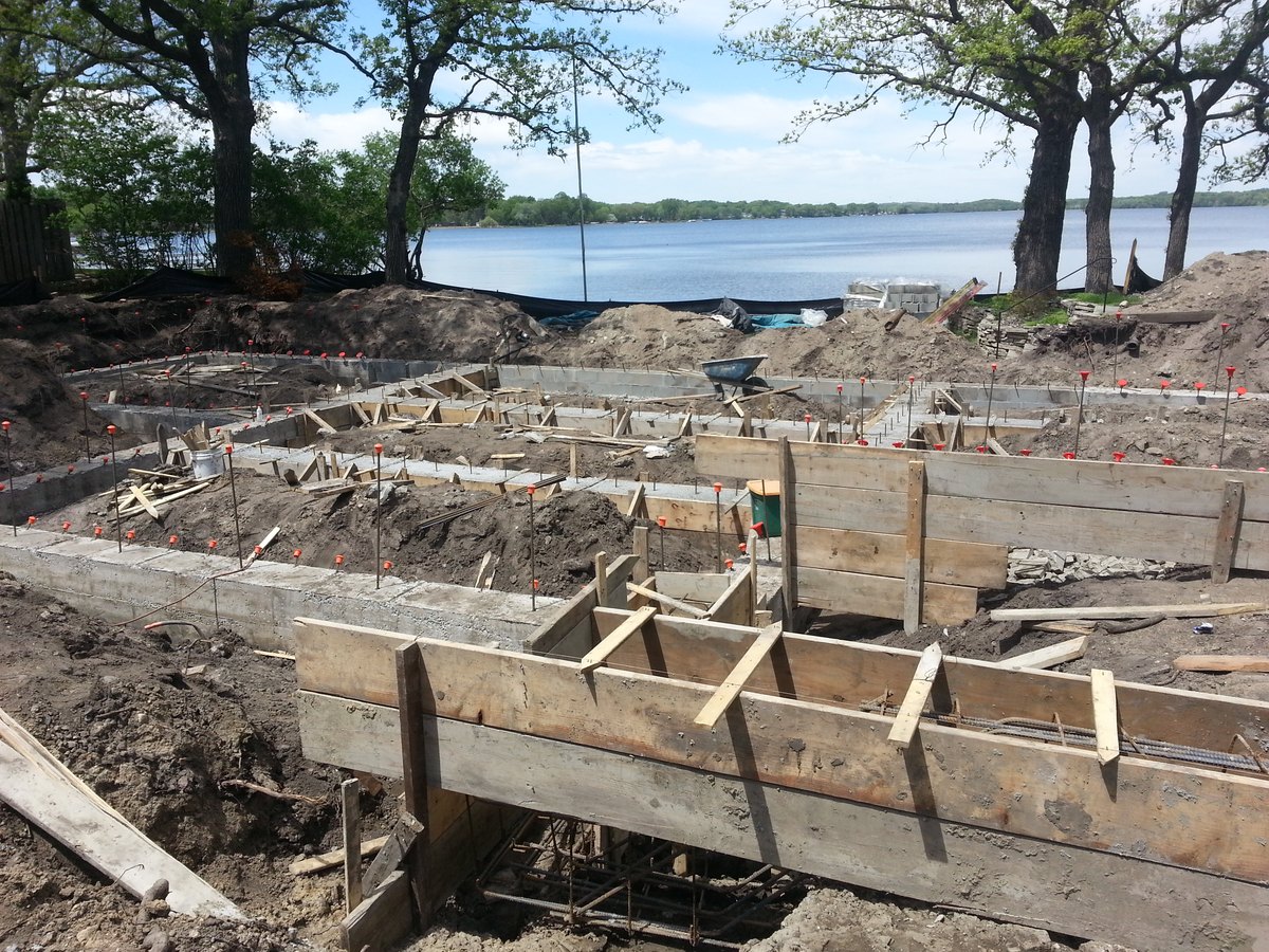 Concrete foundation work and formwork on a site beside a lake.