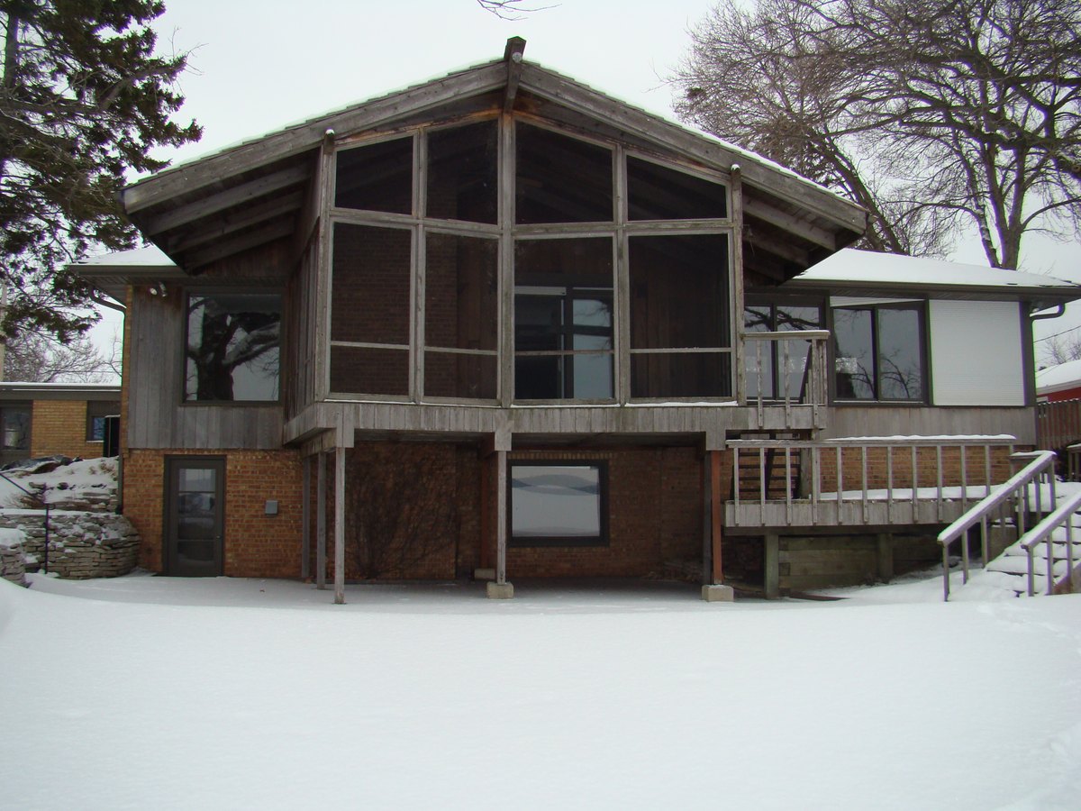 Earlier house with a screened rear gable and wood deck in winter.