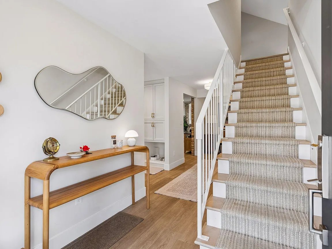Bright entry with painted trim, a console table and a staircase.