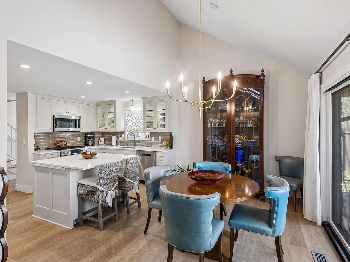 Open connection between a kitchen island and dining table beside patio doors.
