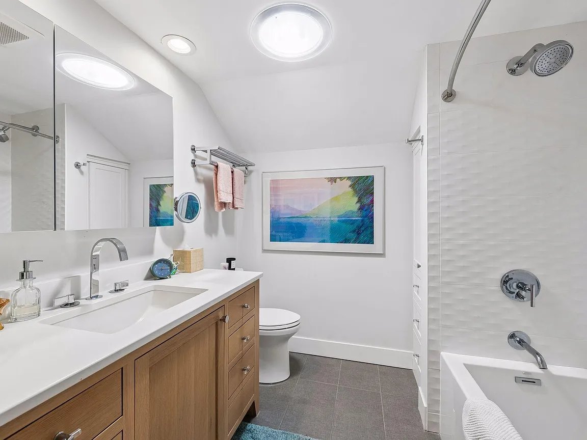 Bathroom with a wood vanity and a tiled tub and shower surround.