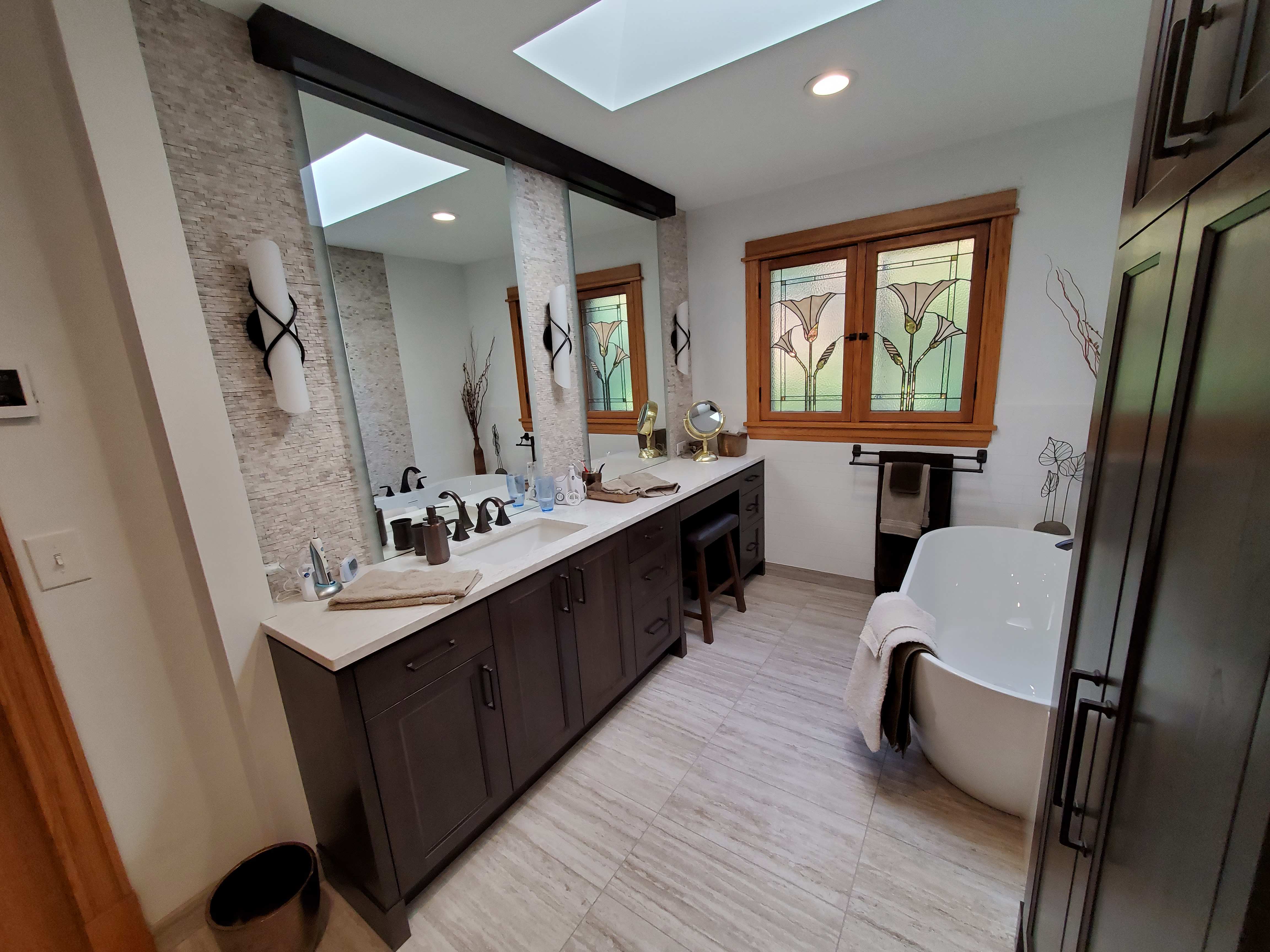 Finished spa-style primary bath with freestanding tub, stained-glass windows, and double vanity