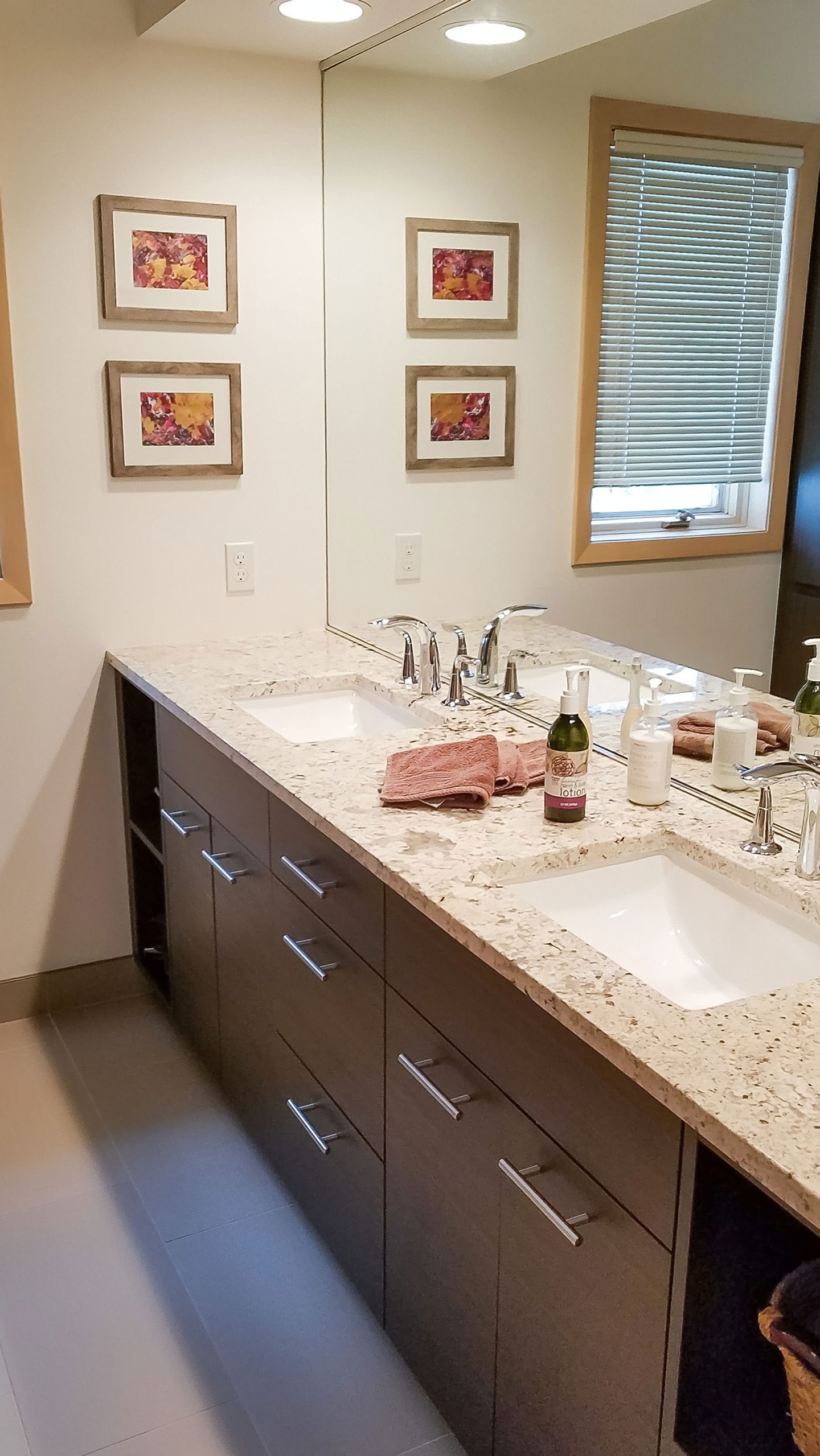 Double vanity with espresso cabinetry, quartz counter, and framed artwork