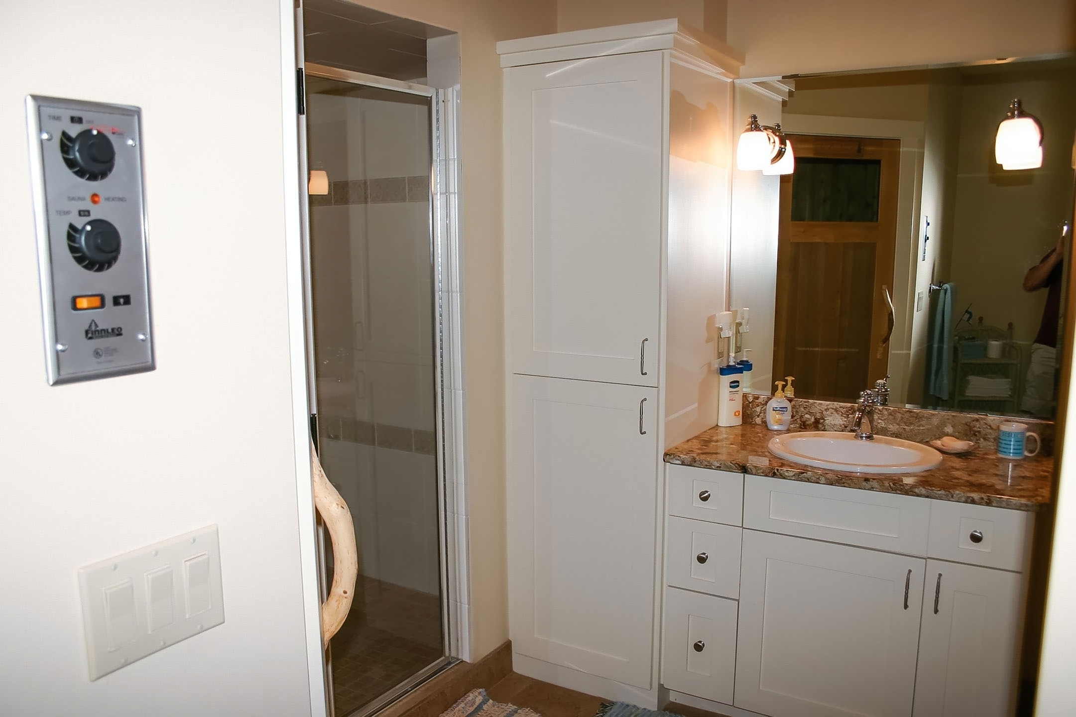 Lower-level bath with white cabinetry, granite top, sauna, and steam shower
