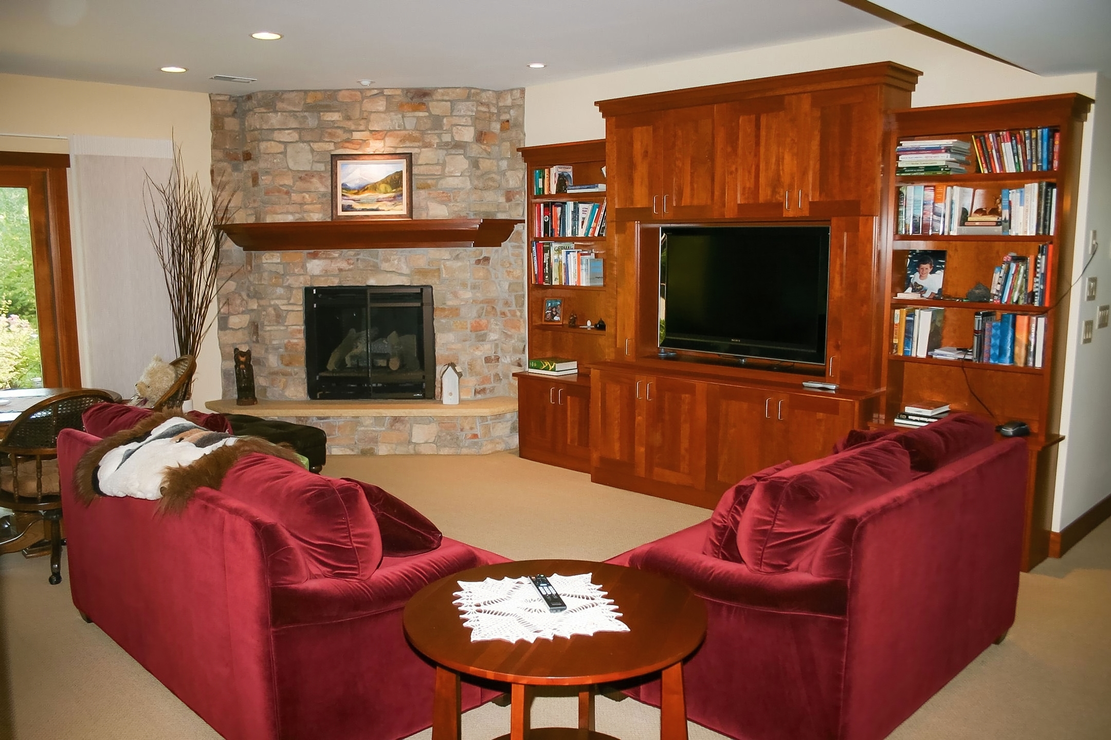 Lower-level great room with a full-height stone fireplace, cherry built-ins, and a walkout
