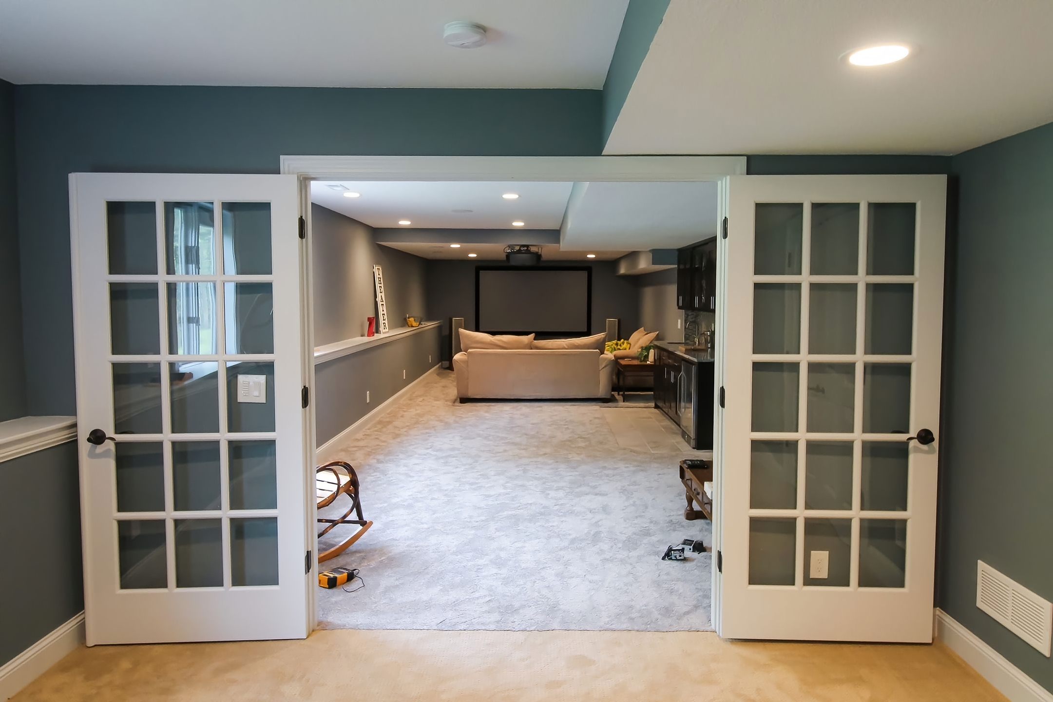 View through french doors into a basement theater area with projection screen