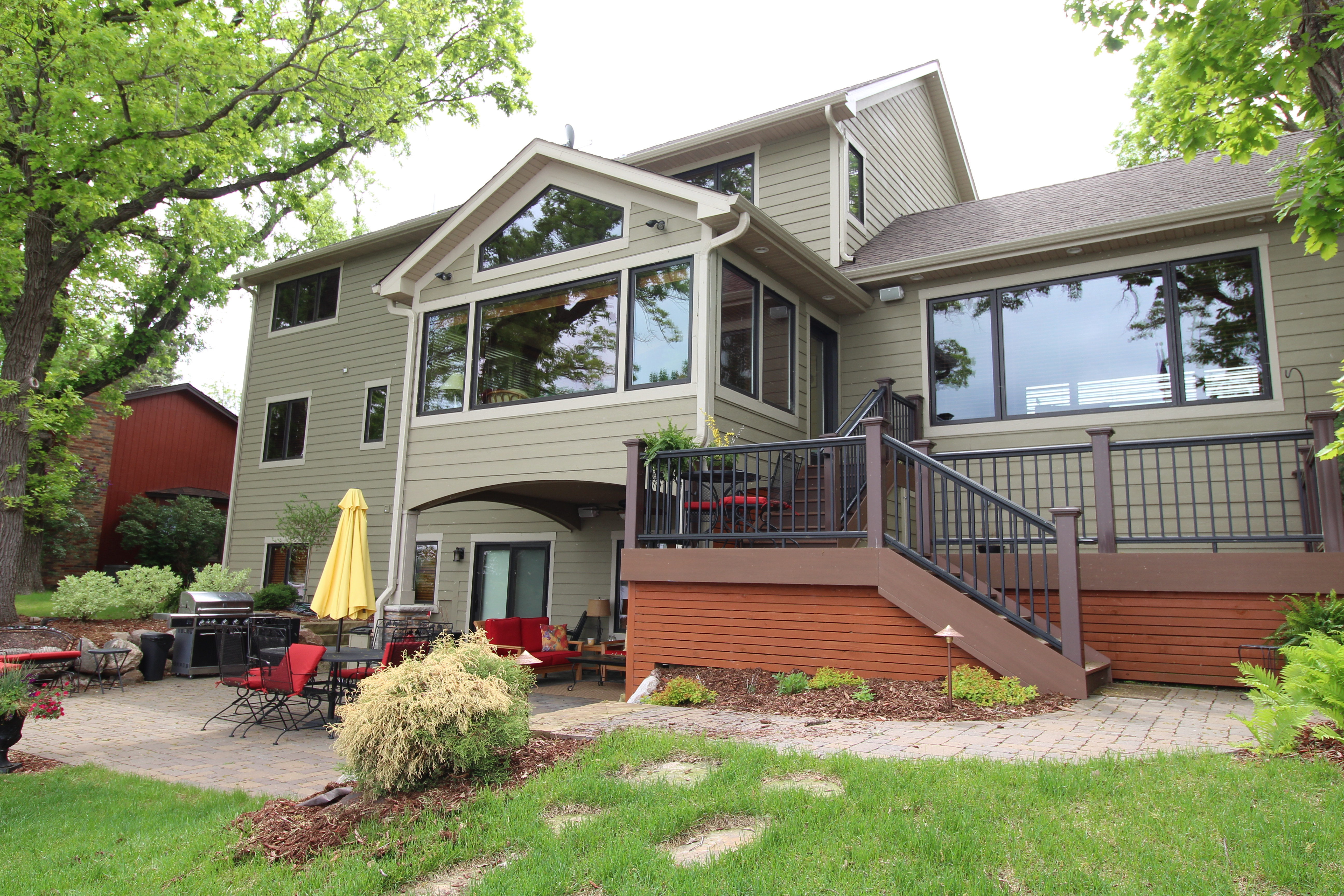 Lake-side elevation of the West Metro custom home with a tiered deck and expansive glass